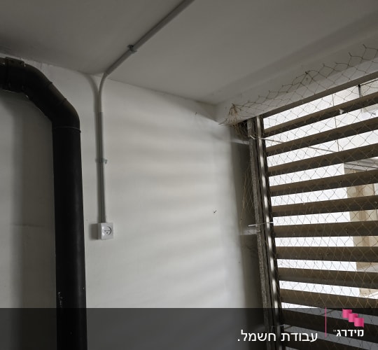 שקע חשמל מותקן על קיר ליד צינור